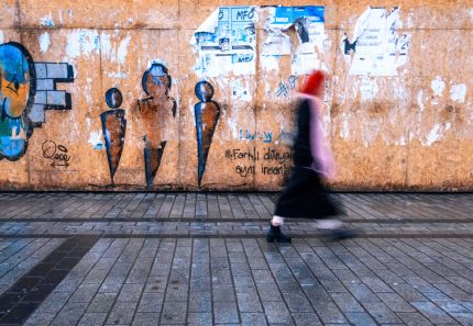 Blurred motion of a pedestrian passing vibrant street art in Istanbul, Türkiye.