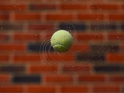 A wet tennis ball is spun and tossed into the air, creating cool spiral effect